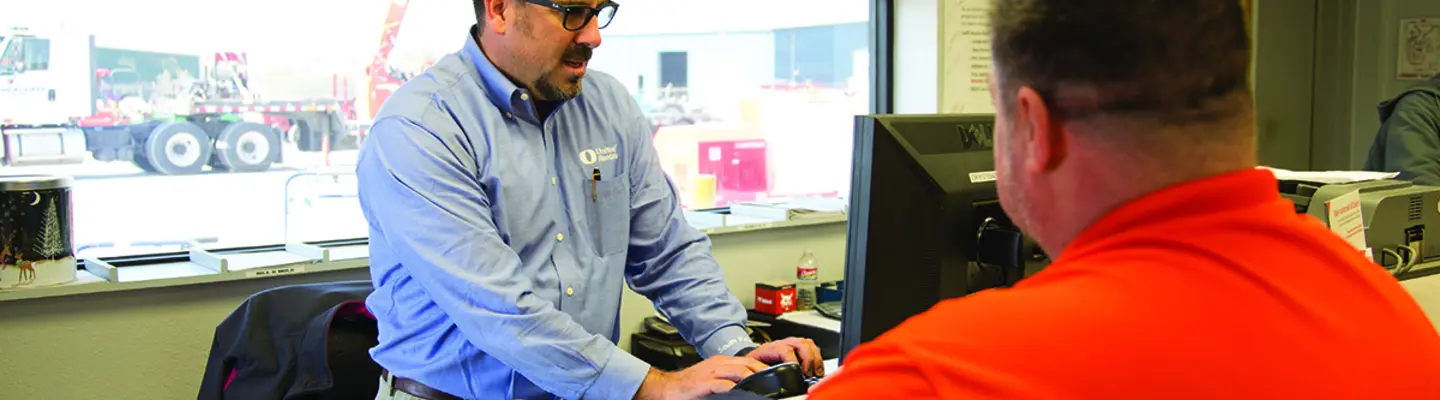 man at computer behind desk with another man