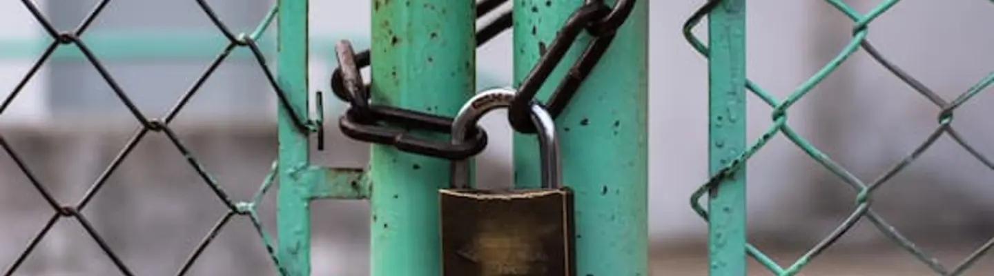 Lock gate secured with chains and signage, restricting access to a hazardous or restricted worksite area.