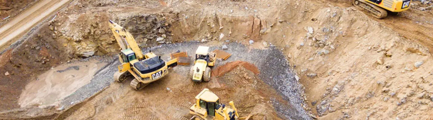 "Excavators assisting construction crews on-site, with safety barriers in place to control access and protect workers."