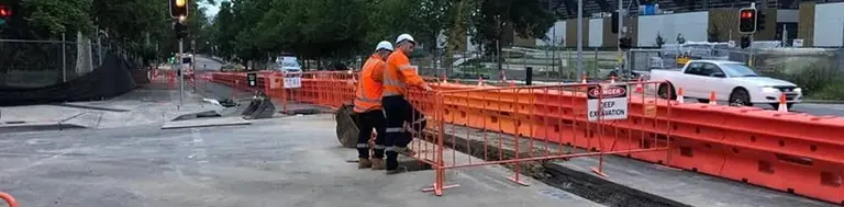 Safety barriers and fencing installed along a light rail track to protect pedestrians and secure the construction area.