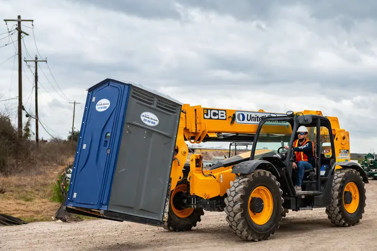Forklift carrying a porta potty