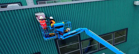 Two workers on boom lift working on a building