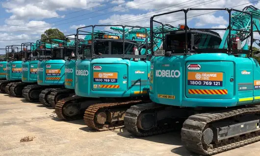 Multiple excavators displayed at a construction site, showcasing equipment used for digging and barrier installation work.