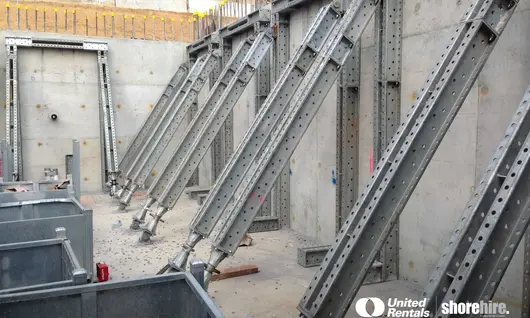 Modular Props are anchored to a concrete retaining wall, providing temporary structural support during construction.