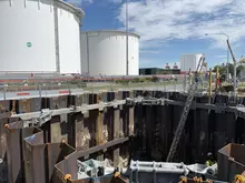 Construction worker installing hydraulic bracing systems in a trench to prevent wall collapse and enhance excavation safety.