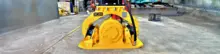 Plate compactor machine on a construction site near safety barriers, used for compacting soil and maintaining ground stability.